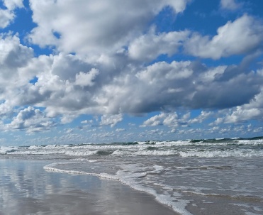 Plaża w Karwi, wzburzony Bałtyk, białe chmury i wakacyjny spacer brzegiem morza.
