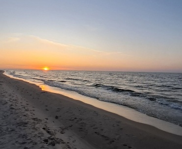 Zachód słońca nad plażą w Karwi, spokojne fale, piaszczysty brzeg i wakacyjny krajobraz Bałtyku.