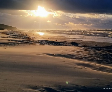 Złoty zachód słońca nad plażą w Karwi, odbicia światła na mokrym piasku i fale Bałtyku.