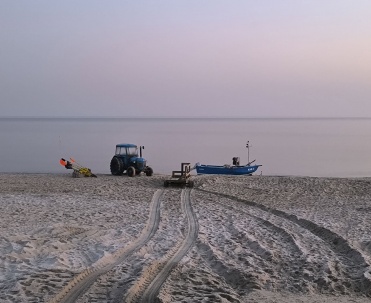 Traktor i łódź rybacka na plaży w Karwi, nadmorski krajobraz, piasek i lokalny klimat Bałtyku.