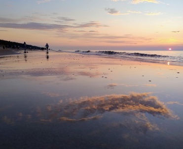 Odbicie zachodu słońca na mokrej plaży w Karwi, Bałtyk i szeroki brzeg morza.