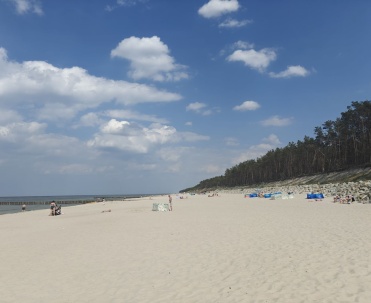Plaża z niewielką liczbą ludzi pod błękitnym niebem. Pogorzelica